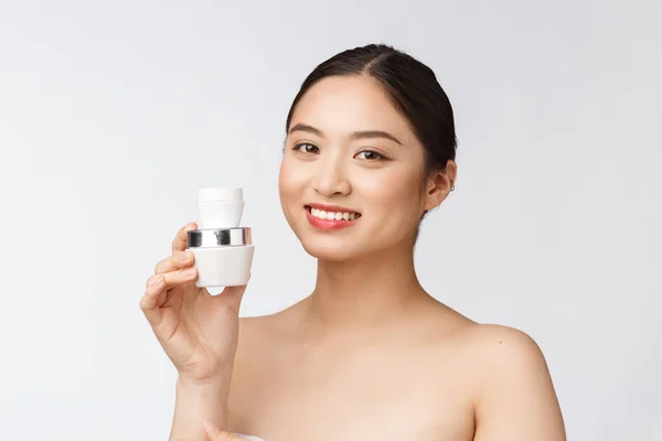 Vacker ung kvinna på vit isolerad bakgrund håller kosmetisk ansiktskräm, asiatisk — Stockfoto