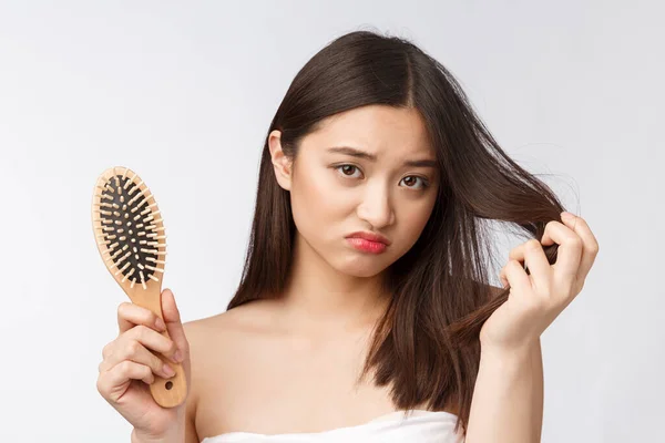 Kesal menekankan wanita muda Asia memegang rambut kering yang rusak di tangan atas putih terisolasi latar belakang . — Stok Foto