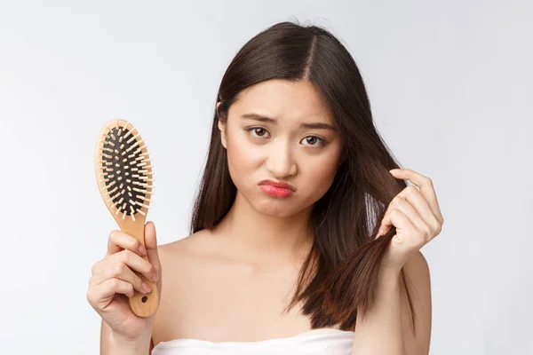 Kesal menekankan wanita muda Asia memegang rambut kering yang rusak di tangan atas putih terisolasi latar belakang . — Stok Foto