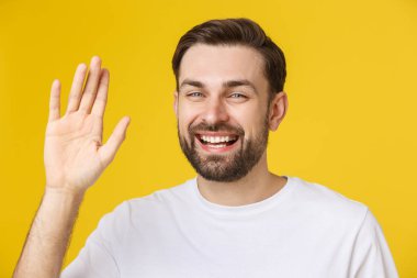 Merhaba, merhaba. Küçük sakallı, beyaz gömlekli, mutlu kahverengi saçlı bir adamın portresi. Kameraya el sallıyor, dişlek bir gülümsemeyle karşılıyor..