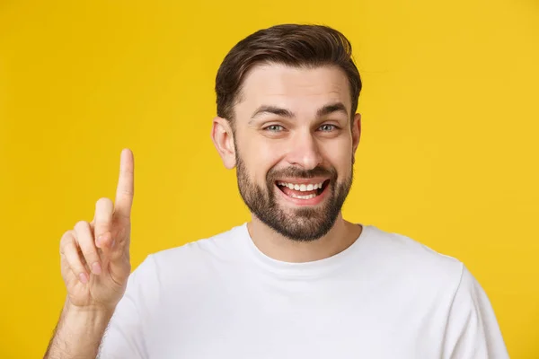 Thinking man isolated on yellow background. Closeup portrait of a casual young man finger up at copyspace. Caucasian male model. — Stock Photo, Image