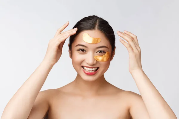 Wanita remaja kecantikan Asia merawat kulitnya dengan penutup mata emas di bawah mata — Stok Foto