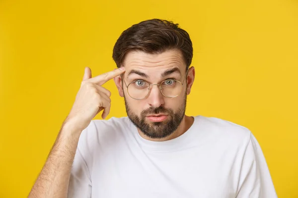 Closeup of young handsome man looking and showing funny face at camera, wearing glass. Isolated view on yellow background. — Stock Photo, Image