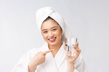 Sağlıklı, su içen genç, güzel bir kadın. Yüzü doğal makyajlı, beyaz arka planda soyutlanmış..