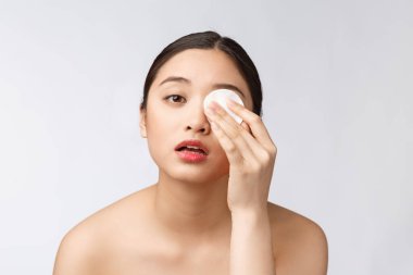 Cilt bakımı yapan kadın yüz makyajını pamuklu bezle temizliyor. Cilt bakımı konsepti. Mükemmel ciltli güzel melez ırk modelinin yüz görüntüsü..