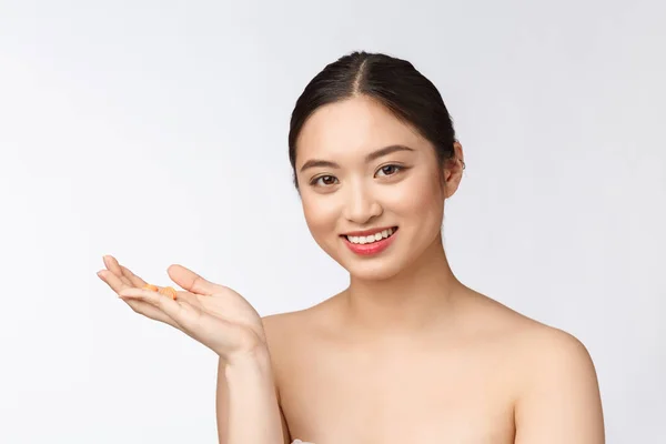 Young attractive asian woman who takes a capsule or pill. Isolated over white background. — Stock Photo, Image