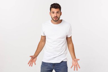 Çekici yakışıklı. Beyaz arka planda tek başına dikilirken sıradan giyinen yakışıklı genç adam.