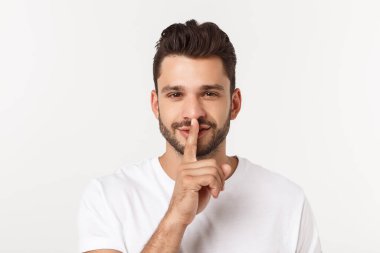 Çekici yakışıklı. Beyaz arka planda tek başına dikilirken sıradan giyinen yakışıklı genç adam.