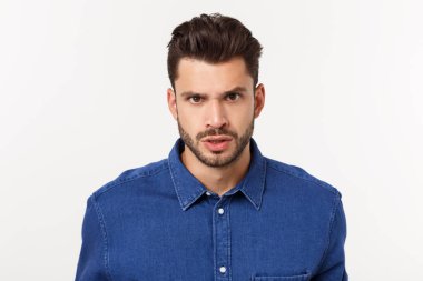 Çekici yakışıklı. Beyaz arka planda tek başına dikilirken sıradan giyinen yakışıklı genç adam.