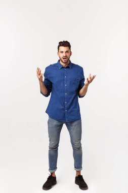 Çekici yakışıklı. Beyaz arka planda tek başına dikilirken sıradan giyinen yakışıklı genç adam.