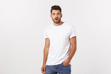 Çekici yakışıklı. Beyaz arka planda tek başına dikilirken sıradan giyinen yakışıklı genç adam.