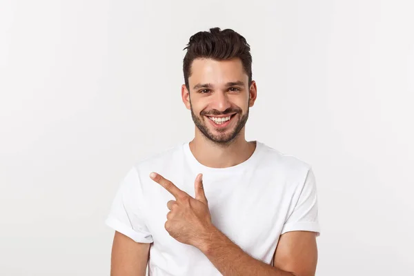 Çekici yakışıklı. Beyaz arka planda tek başına dikilirken sıradan giyinen yakışıklı genç adam.