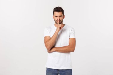 Hayal kırıklığına uğramış sakallı, beyaz arka planda tişörtlü bir gencin yakın portresi..