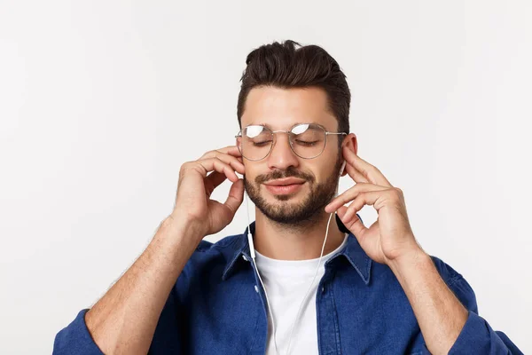 Porträt eines gutaussehenden jungen Mannes, der vor weißem Hintergrund Musik hört. — Stockfoto