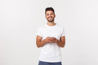 Çekici yakışıklı. Beyaz arka planda tek başına dikilirken sıradan giyinen yakışıklı genç adam.