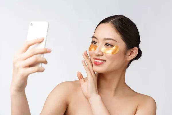 Tutup selfie indah bahagia wanita dengan masker mata di wajah. Wanita dengan masker mata mengambil selfie dengan ponsel di rumah menikmati relaksasi dan — Stok Foto