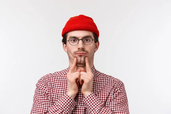 Rolig och söt skäggig kaukasier kille i glasögon och röd mössa, squeez kinder för att göra dubbel haka imitera fyllig chef på jobbet som om kopiera honom hånar, stående vit bakgrund — Stockfoto