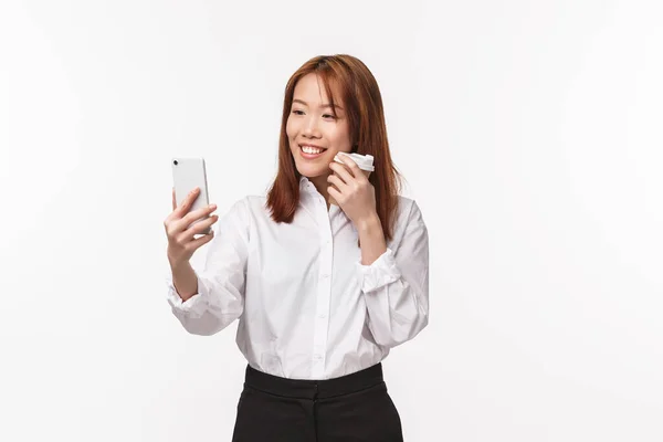Büroarbeit, Menschen und Lebensstil-Konzept. Porträt einer eleganten und hübschen jungen asiatischen Frau, die Selfie macht, Video aufnimmt, um soziale Medien zu posten, App-Filter für ein Foto mit Kaffee zum Mitnehmen verwendet, lächelnd — Stockfoto