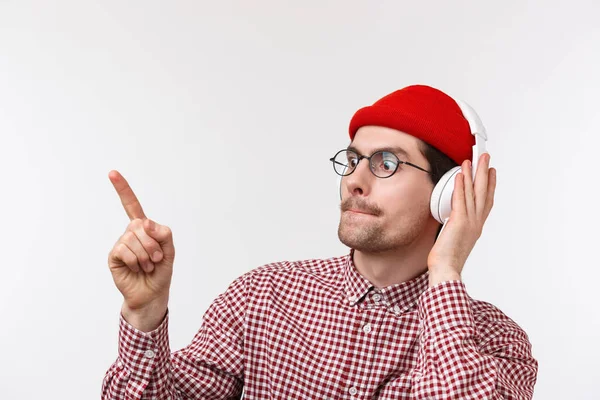 Musique, technologie et concept humain. Gros plan portarit de beau jeune danseur écoutant de la musique dans les écouteurs, se déplaçant vers la chanson préférée du rythme, debout fond blanc — Photo