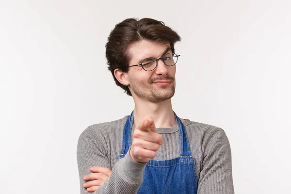 Close-up portrait of cheeky smiling handsome man inviting person start career at his coffee shop, pointing camera and wink hinting friend made good point, standing white background — Stock Photo, Image