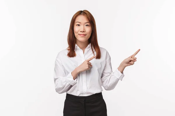 Ritratto di successo abbastanza asiatico signora tutor, imprenditrice puntando il dito destro e sorridente piacevole alla fotocamera come raccontare caratteristiche del prodotto, pubblicità, sfondo bianco — Foto Stock