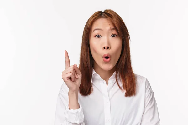 Have solution. Close-up portrait of excited creative asian woman suggest idea, folding lips as saying something, raise finger eureka gesture, make good point, stand white background — Stock Photo, Image