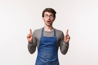 Meraklı ve ilgili bir gencin portresi, barmen yukarı bir şey görüyor, çenesini indiriyor, ilgi çekiyor, barın önünde beyaz arka planda dikiliyor.