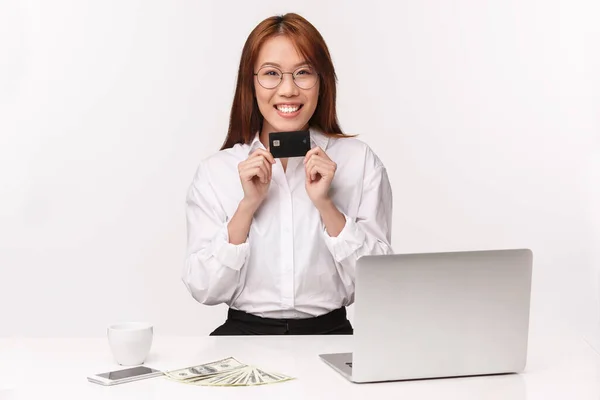 Career, work and women entrepreneurs concept. Close-up portrait of smiling pleasant asian office lady suggest customer new credit card, bank assistant signing deal, sit near laptop money and coffee