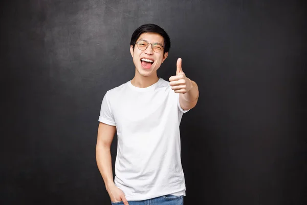 Lebensstil und Menschenbild. Glückliche und zufriedene junge asiatische moderne Kerl Kunde verließ beeindruckt und zufrieden nach dem Besuch tolles Konzert, zeigen Daumen nach oben in Zustimmung und zwinkern freudig — Stockfoto