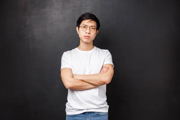 Retrato de hombre macho asiático de aspecto serio confiado en gafas, entrecerrando los ojos cauteloso y mirando la incredulidad de la cámara, cruzar las manos sobre el pecho, no confíe en la persona que habla, fondo negro — Foto de Stock