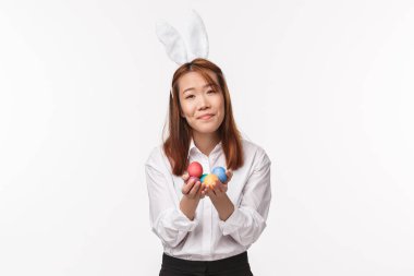 Paskalya tatili, kutlama konsepti. Ortodoks gününü kutlayan tavşan kulaklı aptal kawai dindar bir kadının portresi boyalı yumurtalar tutuyor ve mutlu bir şekilde gülümsüyor.