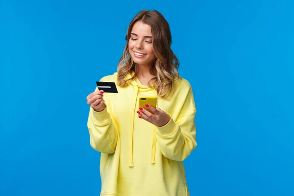 年轻的高加索女人，金发短发，用手机插入信用卡的数字来支付她在网上购物，在网上购物，开心地笑着 — 图库照片