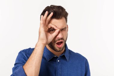 Sakallı yakışıklı genç adam şaşırmış bir yüz ve parmaklarından bakan bir bakışla şoka girdi. İnançsız ifade.