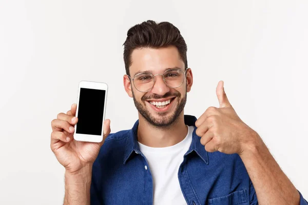 Ung man som visar en tom smartphone skärm med tummen upp isolerad på en vit bakgrund. — Stockfoto