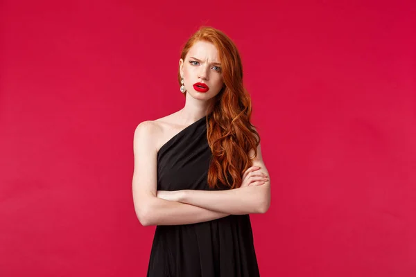 Retrato de mujer pelirroja seria y preocupada, disgustada, vestida de negro, con las manos cruzadas en el pecho, frunciendo el ceño ante la cámara con acusaciones y juicios, escuchando algo frustrante — Foto de Stock