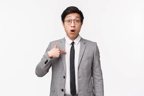 Midja upp porträtt av förvånad och förvirrad asiatisk affärsman, kontorsarbetare pekar på sig själv med misstro och förbryllade uttryck, väljs eller nämns, stående vit bakgrund — Stockfoto