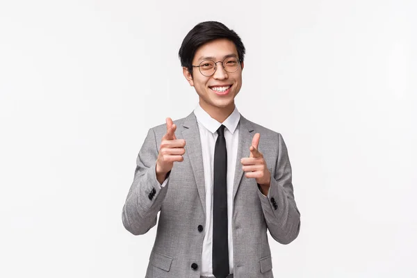 Waist-up Portrait eines frechen, erfolgreichen jungen asiatischen Büroleiters im Anzug, Geschäftsmann auf der Suche nach neuen Mitarbeitern, Zeigefinger-Pistolen-Kamera als Einladung zum Beitritt zum Team, Rekruten, weißer Hintergrund — Stockfoto