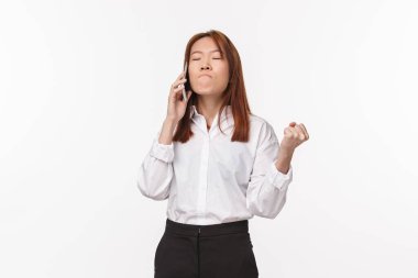 Sakin olmaya çalışırken sabrını kaybeden bir kız sinirli ve sinirli hisseder, yumruğunu sıkar, dudaklarını sıkar, gözlerini kapatır, telefonda konuşur, beyaz bir altyapıya sahip olur.