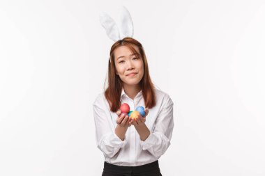 Paskalya tatili, kutlama konsepti. Ortodoks gününü kutlayan tavşan kulaklı aptal kawai dindar bir kadının portresi boyalı yumurtalar tutuyor ve mutlu bir şekilde gülümsüyor.