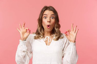 Nutku tutulmuş ve etkilenmiş, beyaz elbiseli güzel bir kızın yakın plan portresi. Gördüğü şey karşısında hayret verici bir performans. Dudaklarını kıvır, 