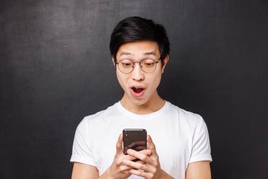 Teknoloji, mesajlaşma ve insan konsepti. Şaşırmış ve heyecanlı erkek öğrencinin yakın plan portresi cep telefonuyla olumlu yanıt alıyor, akıllı telefon ekranına bakın memnun ve şaşırmış
