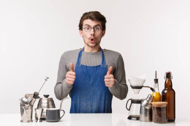 Barmen, kafe çalışanı ve barmen konsepti. Kahve tezgahının yanında duran heyecanlı ve büyülenmiş genç bir adamın portresi. Başparmağını kaldır ve kahve tadını onayla.