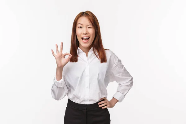 Unboed allegra bella donna asiatica in camicia bianca, mostrare gesto ok, confermare il lavoro fatto, ammiccare e sorridere felice, assicurare tutto bene, tutto perfetto, ottimo lavoro, sfondo bianco — Foto Stock