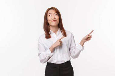 Aptal ve eğlenceli, mutlu Asyalı kadının portresi ilginç bir şey söyleyecek, ürünü tanıtacak, parmaklarını sağa çevirecek ve mutlu bir gülümsemeyle, beyaz arka planda duracak.