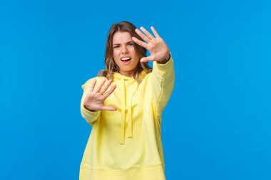 Işığı kapat. Göremiyorum. Hoşnutsuz ve rahatsız edici, sinirli sarışın kız gözlerini ışıktan koruyor, elleri ileri doğru uzanıyor, yeterli jest, şikayet, mavi arka plan