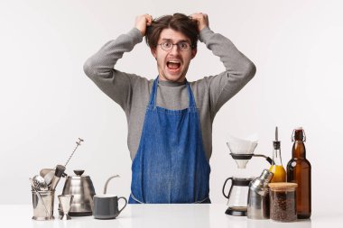 Barista, cafe worker and bartender concept. Portrait of exhausted and pissed-off young male employee pulling hair out of head, screaming distressed, feel pressured, have lots of clients, make coffee