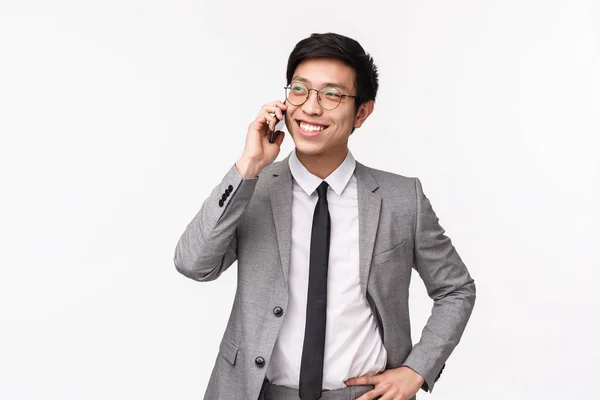 Retrato en la cintura de un joven hombre de negocios asiático guapo, confiado y elegante que llama por teléfono, tiene conversación de negocios, sonríe complacido, discute ofertas financieras, fondo blanco — Foto de Stock