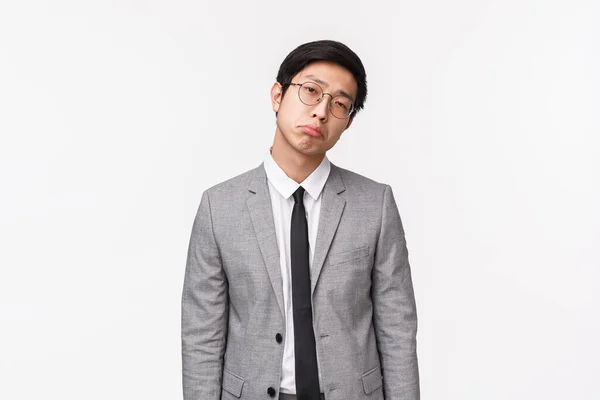Midja upp porträtt av dyster och motvillig, icke imponerad uttråkad asiatisk man i kostym, affärsman som drar missnöjd grimace, ser dömande och skeptisk kamera, stående vit bakgrund — Stockfoto
