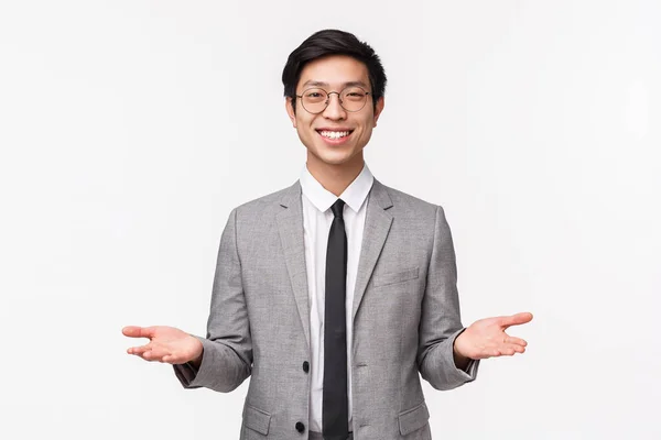 Midja upp porträtt av vänliga utseende stilig ung asiatisk man i kostym, ger två objekt, varianter röd och blå piller, leende som erbjudande fatta beslut, hålla något på handflatorna — Stockfoto