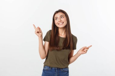 Gri arka planda yalnız duran mutlu ve şaşırmış genç bir bayan portresi. Kamera işaret ediyor.